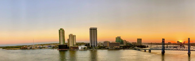 the miami skyline with a bridge over a body of water at sunset.