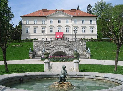 A fountain in front of a large white building in tivoli park in ljubljana