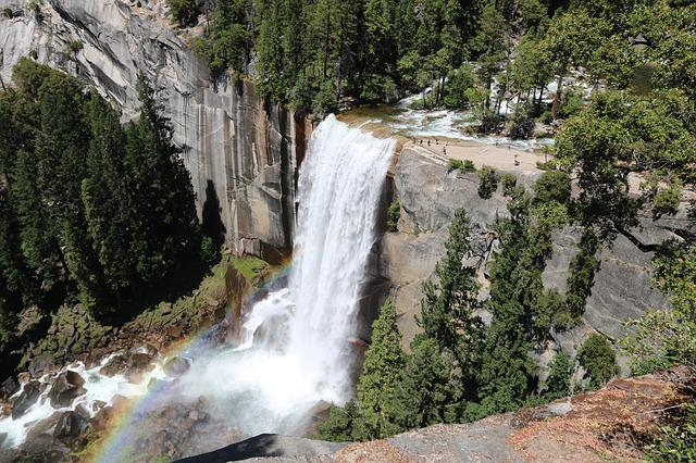 A waterfall with a rainbow in the middle of it in yosemite np