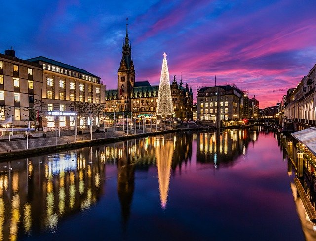 There is a christmas tree in the middle of hamburg next to a river at Weißerzauber On Jungfernstieg