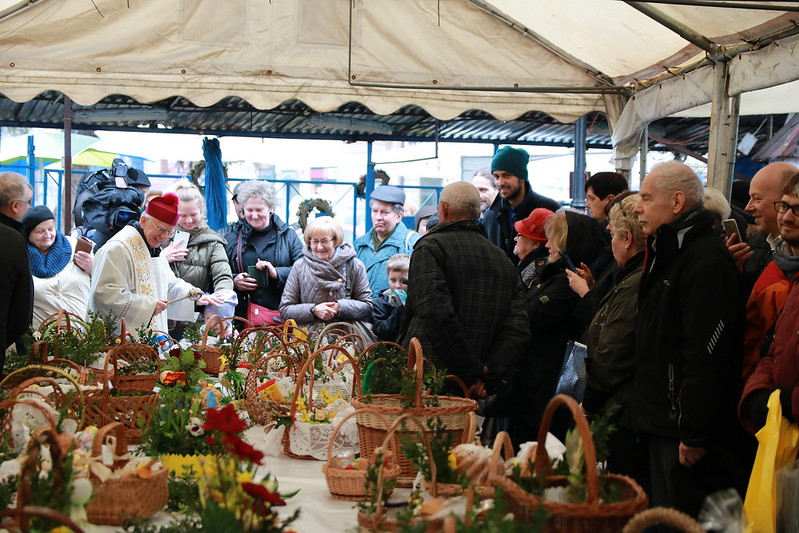 A group of people are gathered under a tent looking at baskets in Krakow