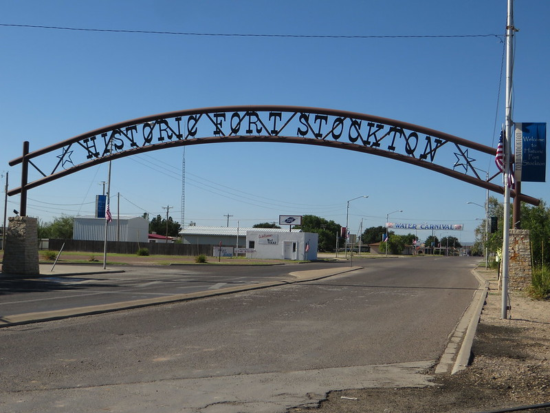 A metal archway over a road that says historic fort stockton
