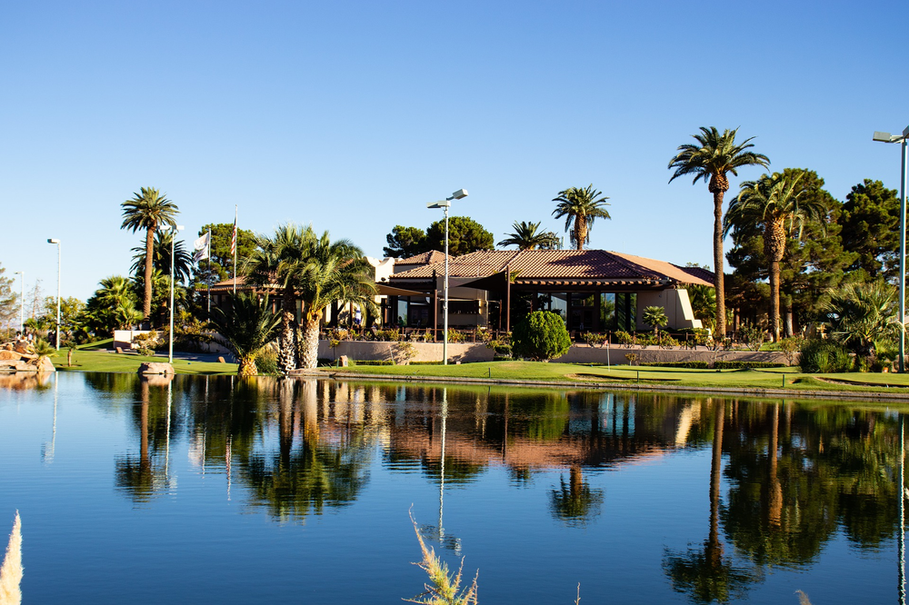 A house sits on the shore of a lake in henderson surrounded by palm trees.