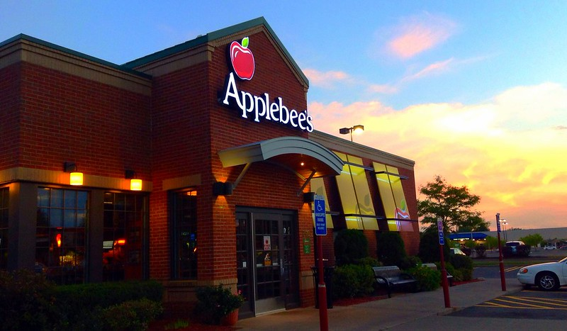 An applebee 's chain restaurant with a car parked in front of it