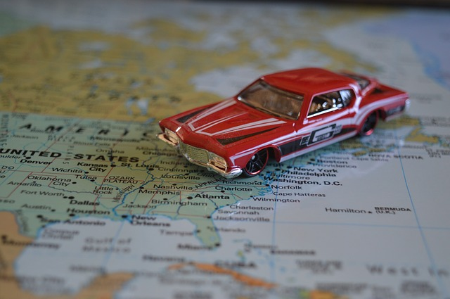A red toy car is sitting on top of a map of the united states.