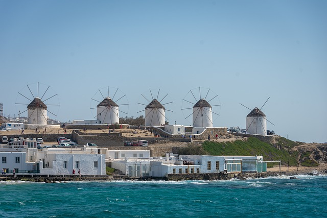 The flour mills of mykonos sitting on top of a hill next to the ocean.