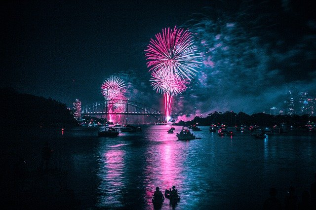 A group of people are watching fireworks over a body of water.