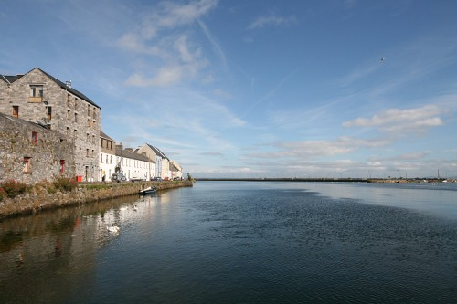 A large body of water surrounded by buildings on a sunny day in Galway