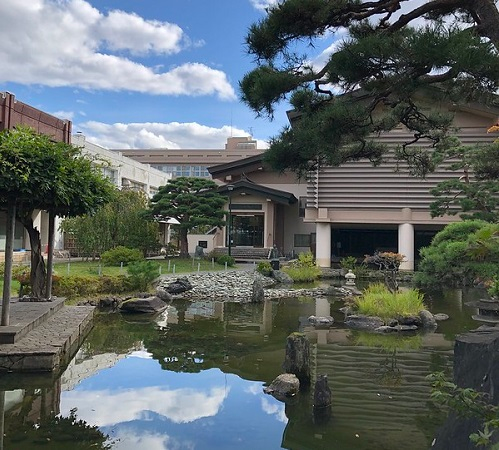 A large building in Amori City with a pond in front of it