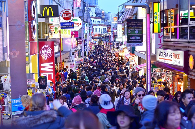 A crowd of people are walking down a busy street in Tokyo at night