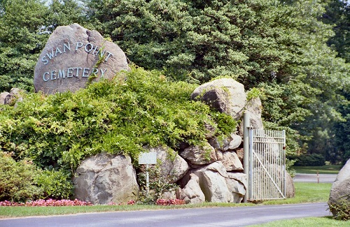 The entrance to swan point cemetery is surrounded by rocks and trees.
