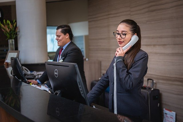 A woman is talking on a cell phone at a hotel reception desk.