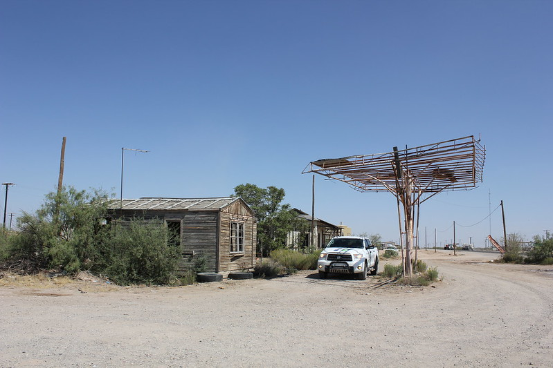 A white truck is parked in front of an old building in Orla ghost town