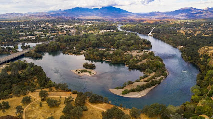 An aerial view of a river in redding surrounded by trees and mountains.