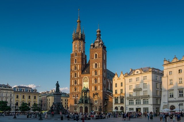 A large building with a clock tower in the middle of a square in Krakow