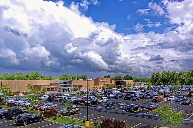 A lot of cars are parked in a parking lot in front of a building.