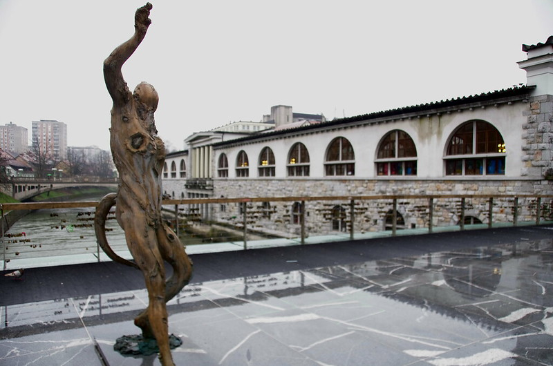 A statue of a man standing in front of a building on Ljubljana's Butcher's Bridge