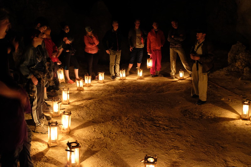 A group of people are standing in a circle holding lanterns in a cave at Carlsbad Caverns National Park