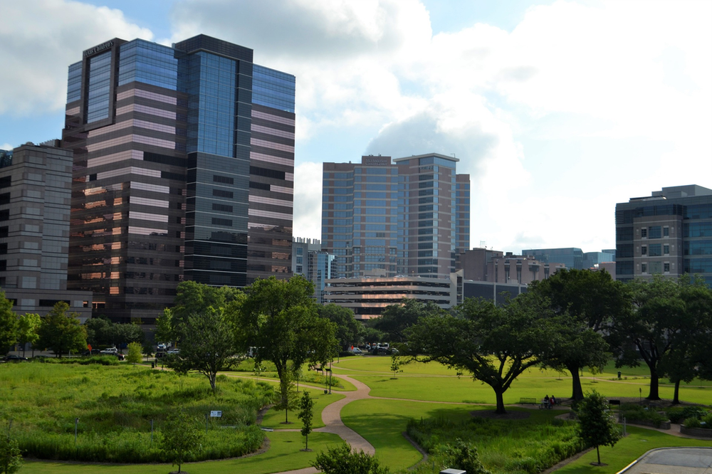 A park in the middle of Houston with tall buildings in the background.