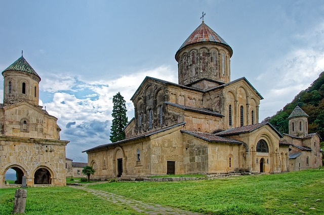 A large church with a cross on top of it is sitting on top of a lush green hillside in Georgia.
