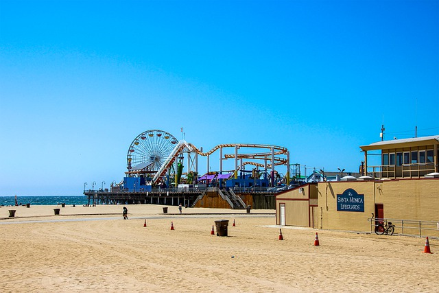 santa monica beach with a ferris wheel and a roller coaster in the background.