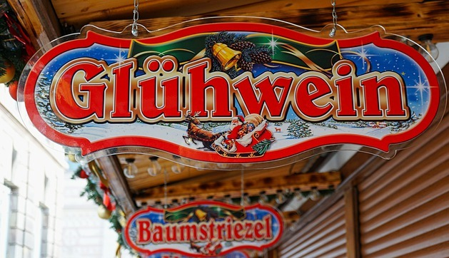 A sign for glühwein is hanging from the roof of a building at the winter pride market
