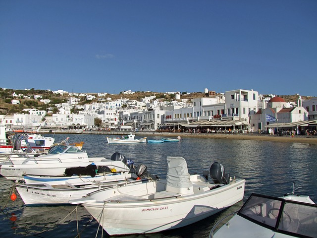 Several boats are docked in mykonos harbor with buildings in the background