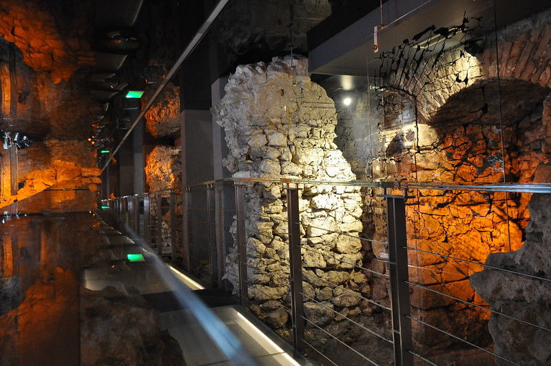 A room with a lot of stone walls and a glass walkway