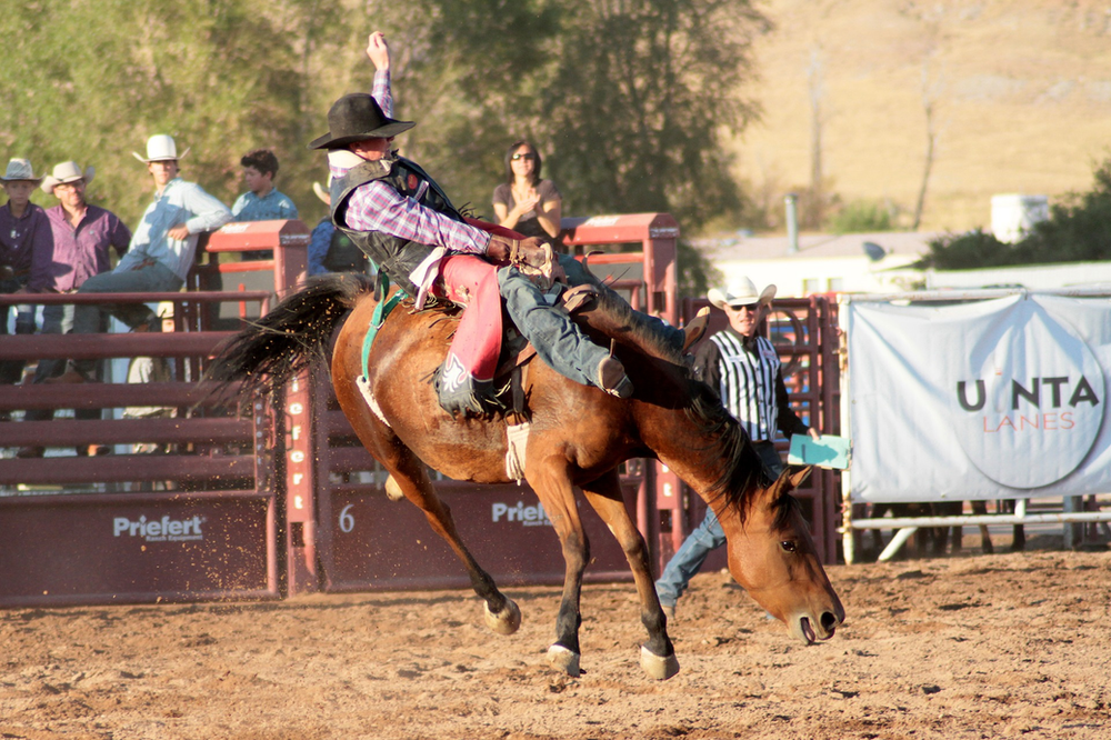 A man is riding a horse in a rodeo arena