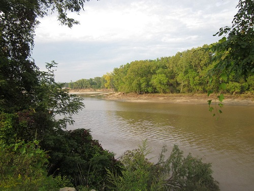 A large body of water surrounded by trees and bushes beside the mohawk hudson hike bike trail