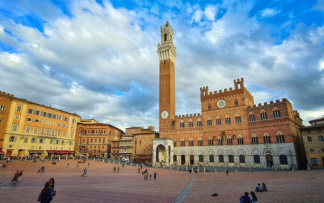 A large building with a clock tower in the middle of a square in Tuscany