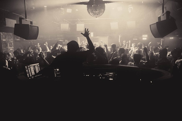 A dj is playing music to a crowd of people in a miami club.