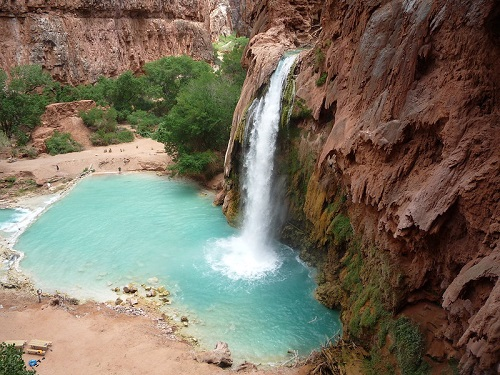 havasu falls is surrounded by rocks and trees and is surrounded by a large body of water.