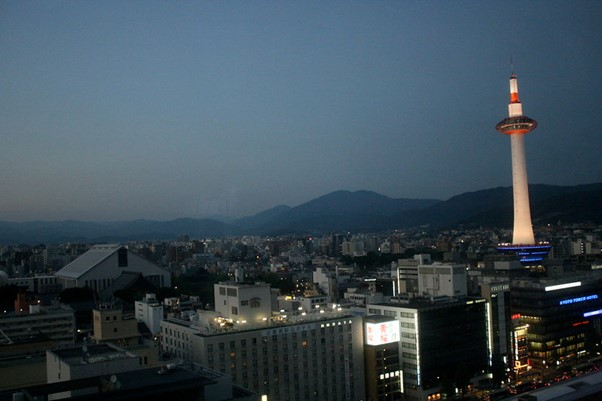 An aerial view of kyoto and the kyoto tower at night with mountains in the background
