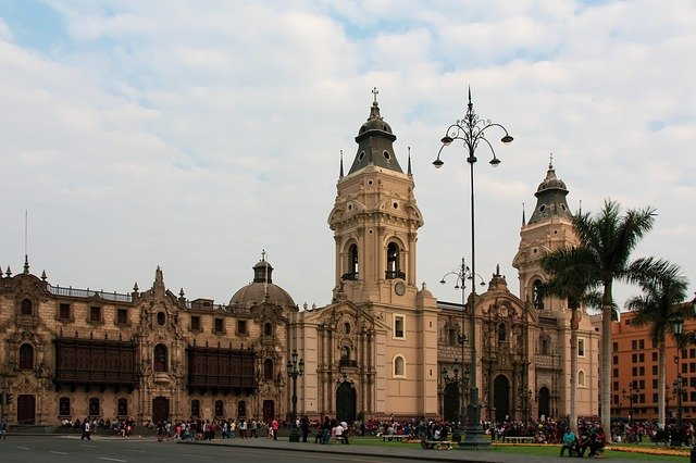 A large building with a bell tower and palm trees in front of it in Lima