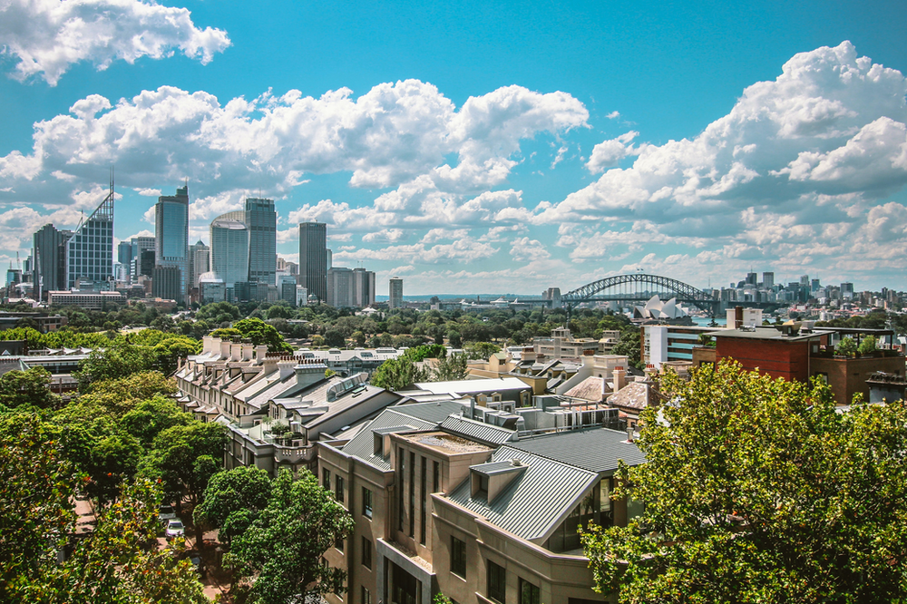 An aerial view of Sydney with buildings and trees in the foreground.
