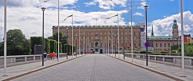 A bridge leading to stockholm palace with flags flying in front of it.