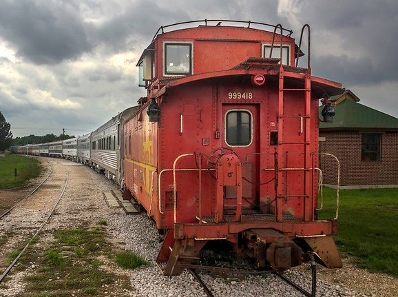 A red train car with the number 90148 on it in Austin hill country