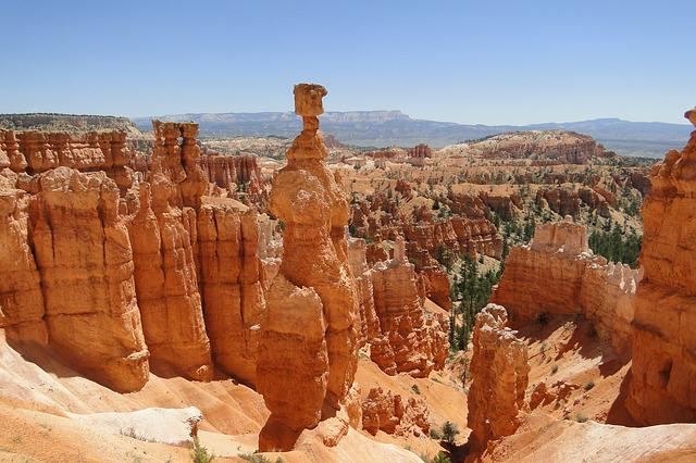 A view of a canyon in Utah with hoodoos and mountains in the background