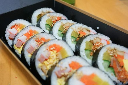 A box filled with a variety of gimbap rolls