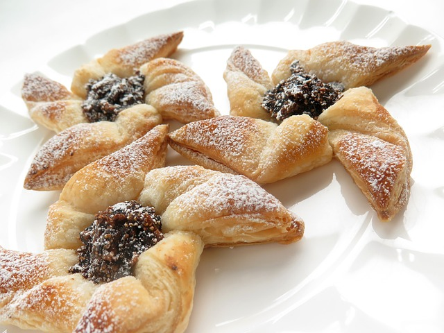 A white plate topped with a bunch of traditional Finnish pastries with powdered sugar on them