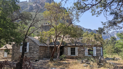 The Wallace E. Pratt House is surrounded by trees and mountains in guadalupe mountains np.