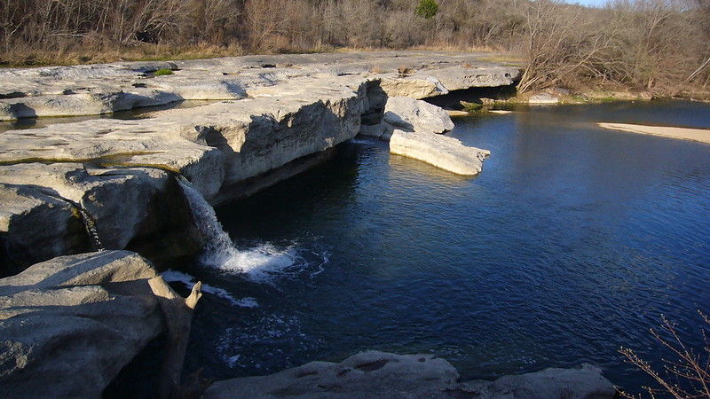A river with a waterfall in the middle of it in McKinney Falls State Park