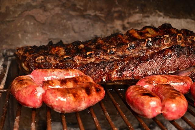Ribs and sausages are cooking on a grill at the Salt Lick