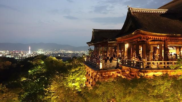 Kiyomizu-Dera temple is lit up at night with a city in the background.