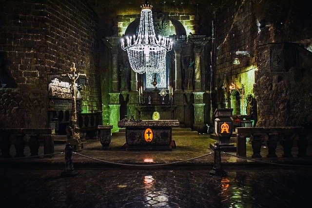 A church with a chandelier hanging from the ceiling and a cross on the altar.