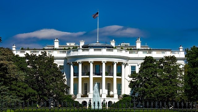 The white house in Washington d.c. is surrounded by trees and a fountain.