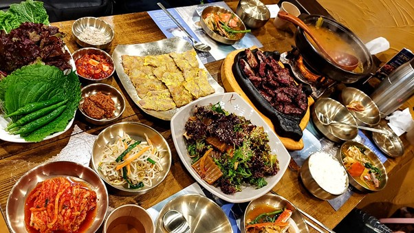 A table topped with plates of food and bowls of South Korean food.
