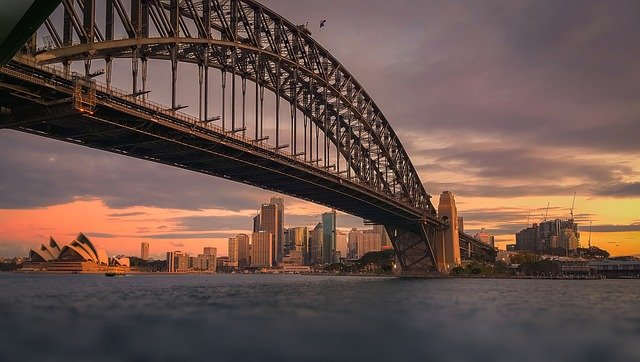 A bridge over a body of water with Sydney in the background.
