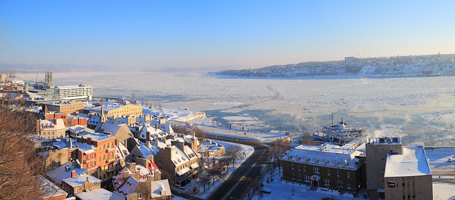An aerial view of quebec city covered in snow next to a body of water.